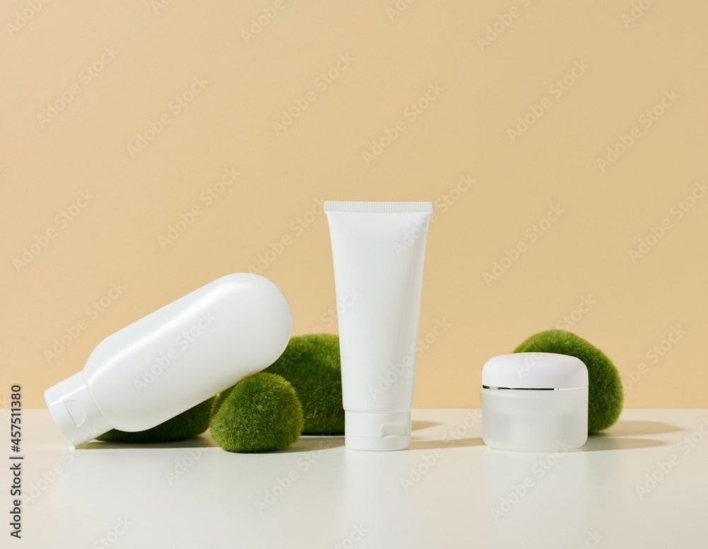 empty white plastic tube, jar with a crusher near stones with moss on a beige background. Cosmetic products for branding gel, cream, lotion, shampoo. Mock up
