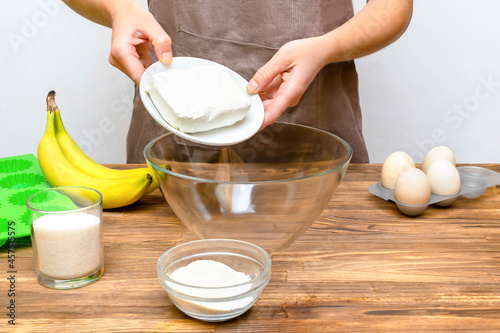 Caucasian woman chef in apron preparing ingredients for making cottage cheese banana muffins cupcakes casserole at home kitchen cuisine, online cooking, recipe instruction