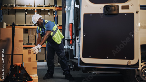 Handsome Black Male Retail Warehouse Worker  Loads Cardboard Boxes in  Delivery Truck. Logistics Retail Center, Delivering e-Commerce Online Orders, Food, Medicine Supply.