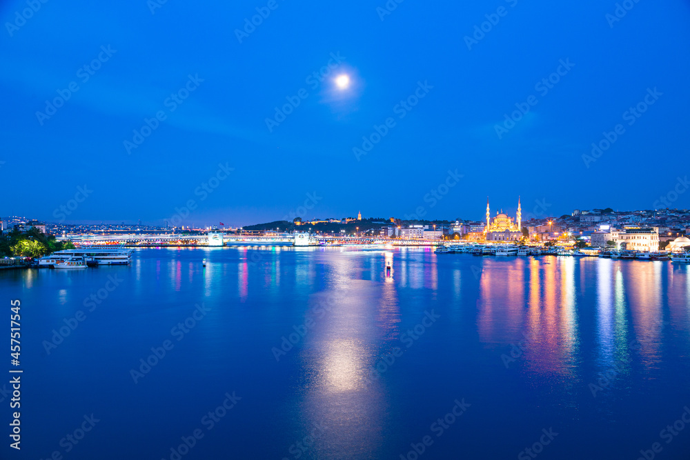 トルコ　イスタンブールの月に照らされた金角湾の夜景と旧市街にあるライトアップされたニューモスク