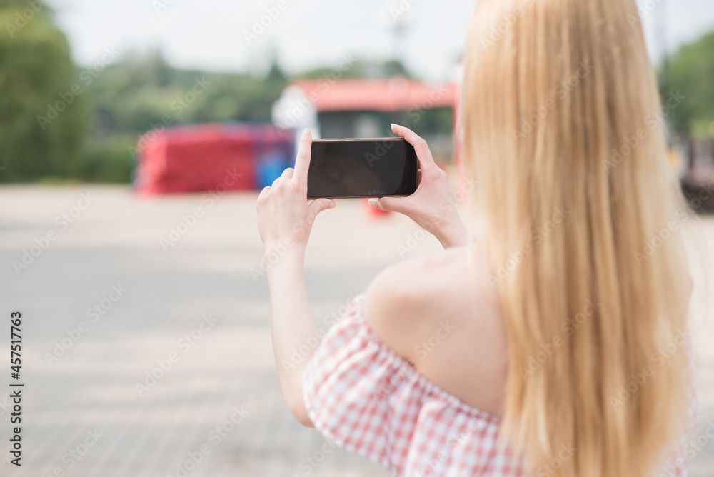 Beautiful caucasian blonde girl holding a smartphone in her hands and taking picture