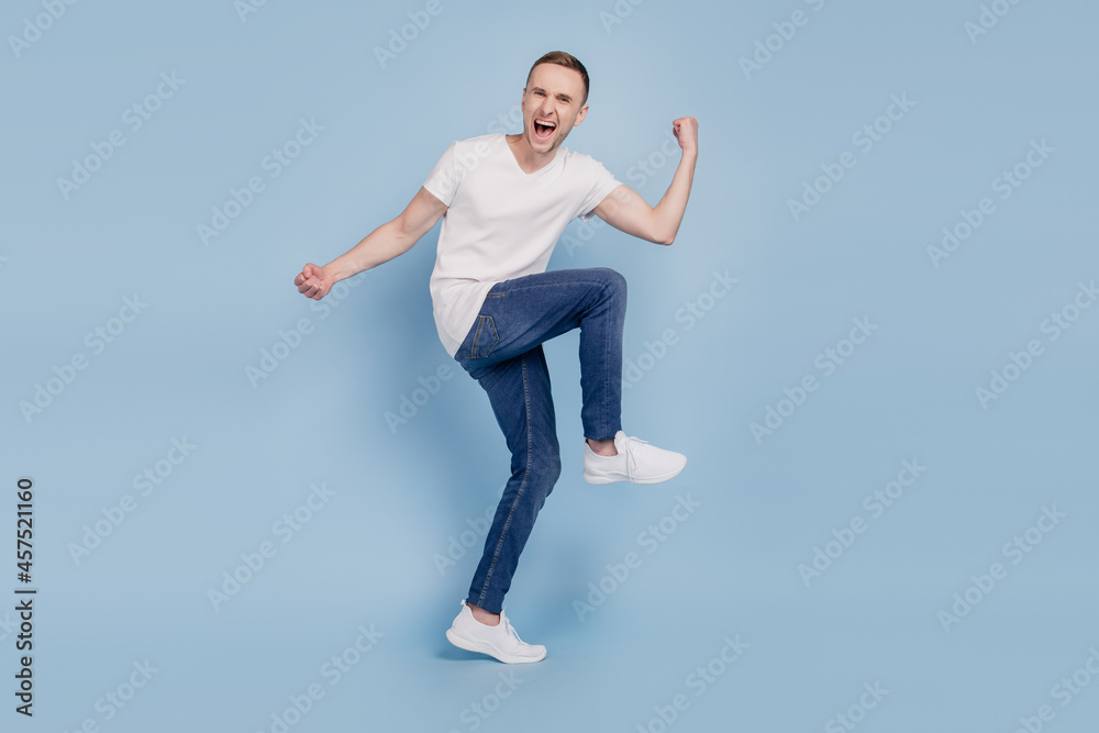 Full size photo of young cheerful man happy positive smile celebrate win victory champion fists hands isolated over blue color background