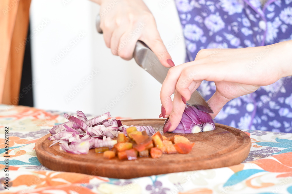a woman cutting onions into small pieces on a wooden board