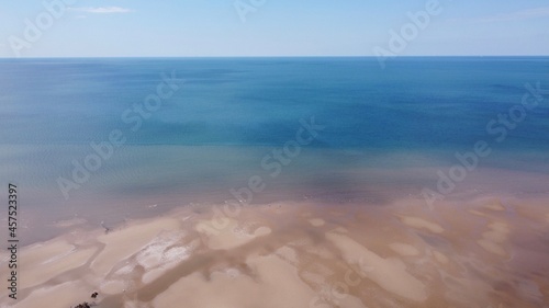 Drone image of a sandy beach with blue sea and a blue sky background. Taken in Lytham England. 
