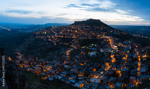 トルコ　山の斜面に広がるマルディンのライトアップされた旧市街の夜景と山頂に立つマルディン城 © pespiero