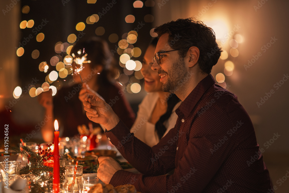 holidays and celebration concept - multiethnic group of happy friends with sparklers having christmas dinner at home holidays and celebration concept - multiethnic group of happy friends with sparklers having christmas dinner at home