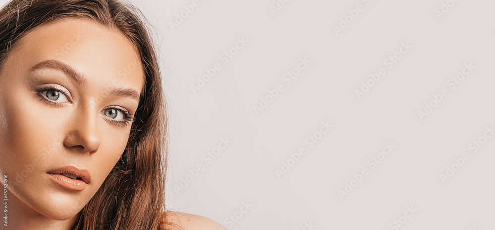 Obraz premium Beautiful young girl smiling and posing looking at the camera on a white isolated background with mockup. Positive brunette woman. Kind look. Beauty face