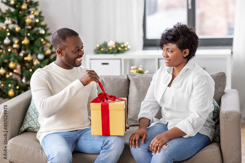 holidays, celebration and people concept - happy african american couple with christmas gift at home holidays, celebration and people concept - happy african american couple with christmas gift at home