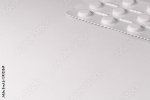 White pack of tablets on a white background. A packet of tablets is placed in the corner of the photo. Free space for text, copy space