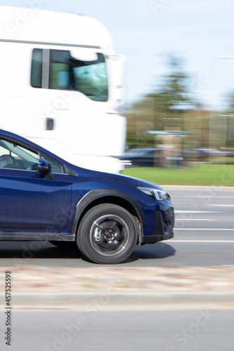 View of a blue car from the side, a fast driving car in traffic. Motion blur.