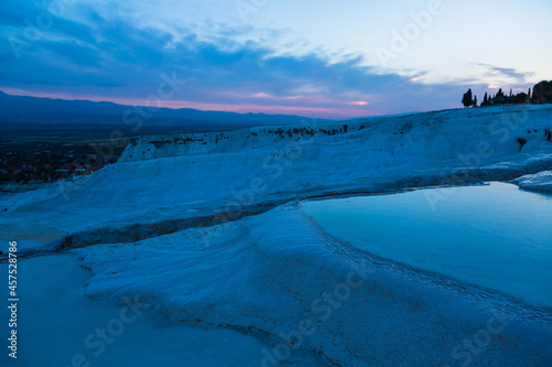 トルコ 夕暮れ時のヒエラポリス・パムッカレの石灰棚と青い水面