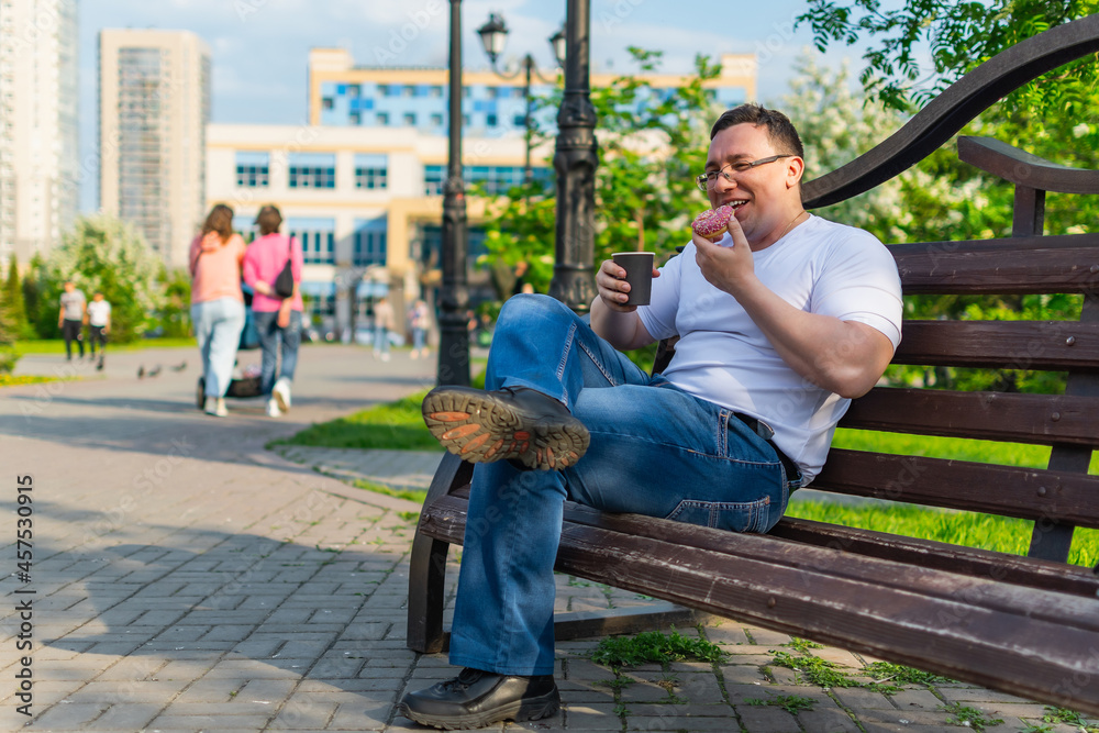 Obraz premium Happy man enjoying delicious donut and laughing while sitting on the bench