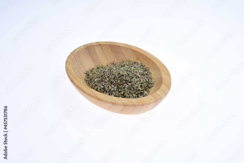 Marjoram. A spice in a wooden bowl on a white background. Food. Marjoram. A spice in a wooden bowl on a white background. Food.