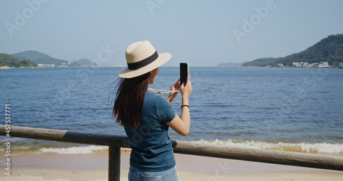 Woman use cellphone to take photo at beach