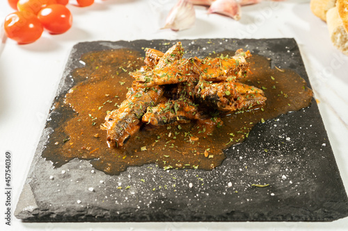 Appetizer served on a slab of sardines with tomato sauce and herbs with some toast bread. Diferential focus. photo