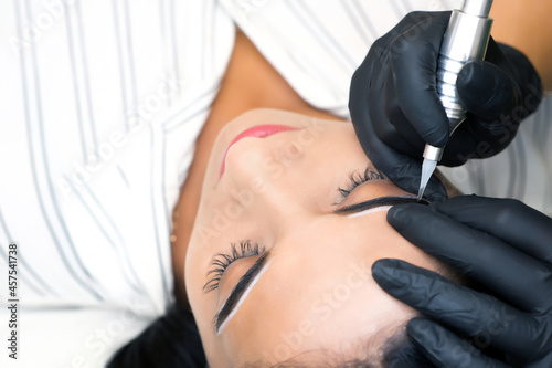 Beautician makes permanent eyebrow makeup on the face