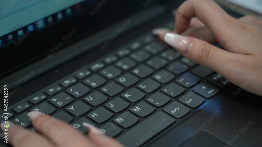Close shot for female white hands with long nail and pink polish typing on dark laptop's keyboard Close shot for female white hands with long nail and pink polish typing on dark laptop's keyboard