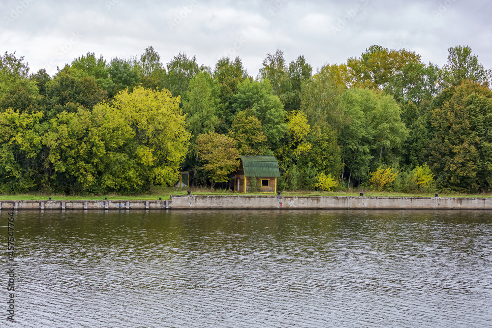 Scenic river landscape with green trees in early autumn