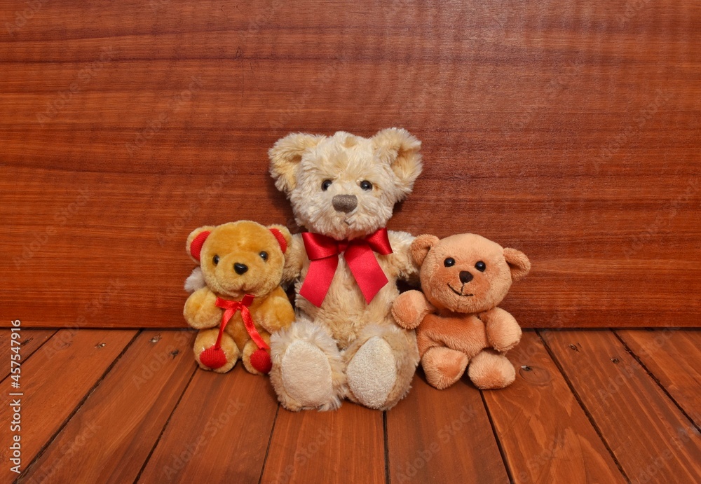 Obraz premium teddy bear with red ribbons. Wooden background 