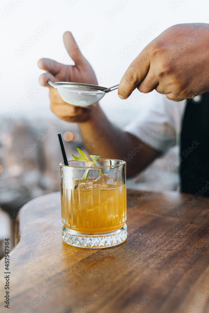 Crop mixologist adding ingredient to cocktail with mint leaves Crop mixologist adding ingredient to cocktail with mint leaves