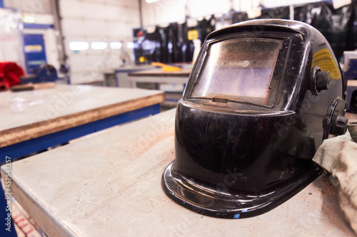 Welding helmet on a workshop table bench with tools in the background