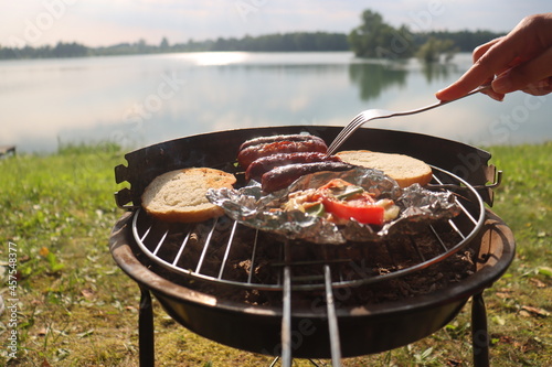 grilled sausage at the summer camp. Vacation in nature near the lake in the early morning