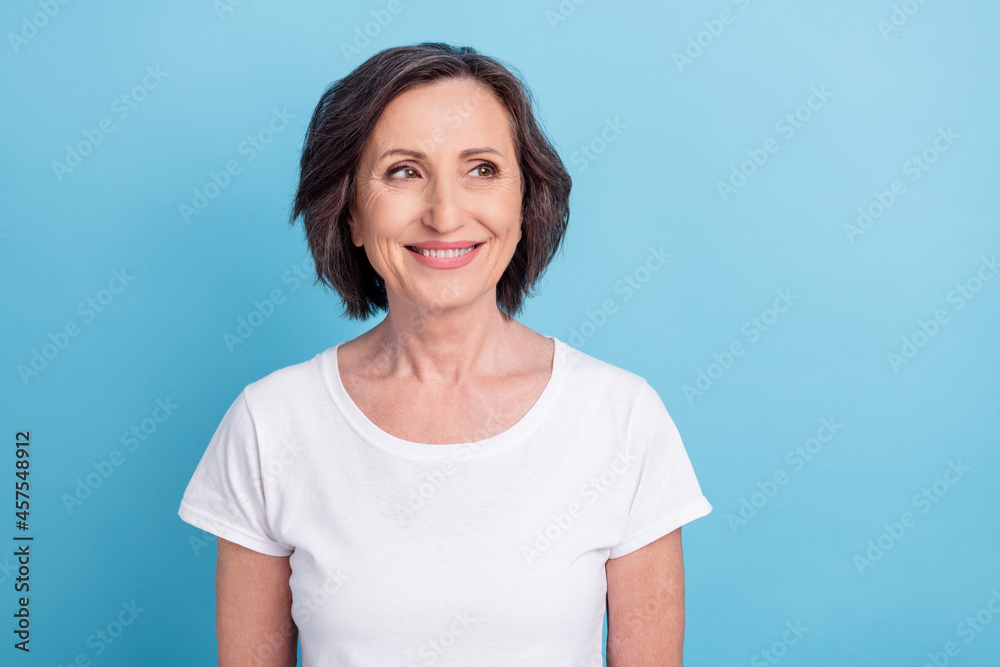 Photo portrait senior woman smiling looking blank space in white t-shirt isolated pastel blue color background Photo portrait senior woman smiling looking blank space in white t-shirt isolated pastel blue color background