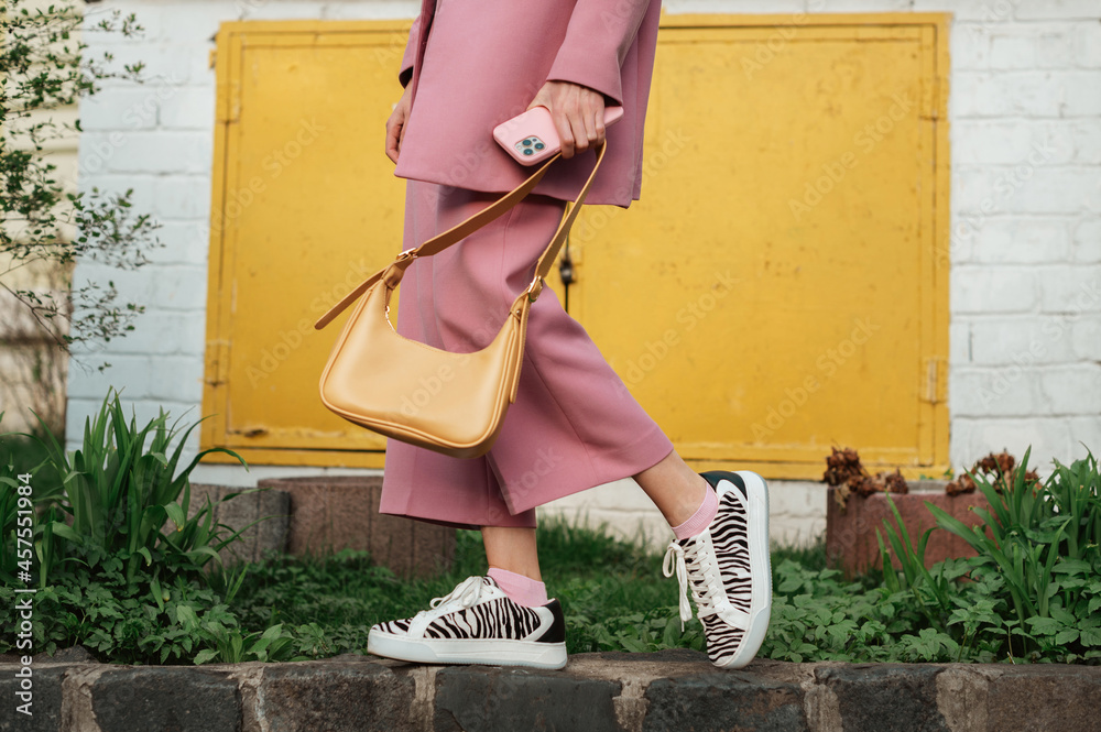 Foto Stock Street fashion elements: woman wearing trendy outfit with pink  suit, zebra print sneakers, holding yellow faux leather handbag. Copy,  empty space for text | Adobe Stock