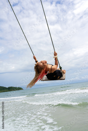 Asian woman smiling on beach swing with sea and sky