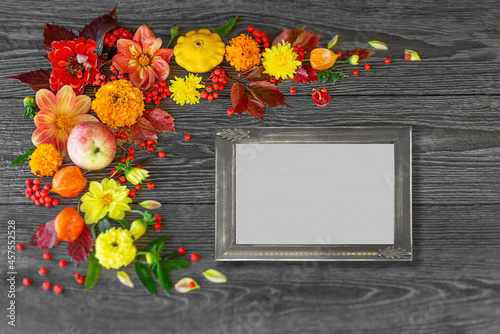 Vintage photo frame with natural autumn orange flowers leaves and pumpkins on a dark wooden background with raindrops. Place for your text or photos. Autumn holiday concept. Postcard, congratulations