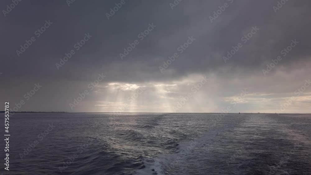 Open North Sea with Dramatic Sky after a Rain Storm. Dark Clouds and Rays of Sunshine. Filmed from the back of a boat. Open North Sea with Dramatic Sky after a Rain Storm. Dark Clouds and Rays of Sunshine. Filmed from the back of a boat.
