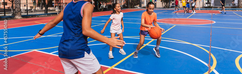 Panoramic of children playing basketball on a court.
