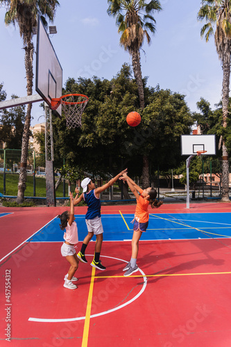 Children playing basketball on a court.