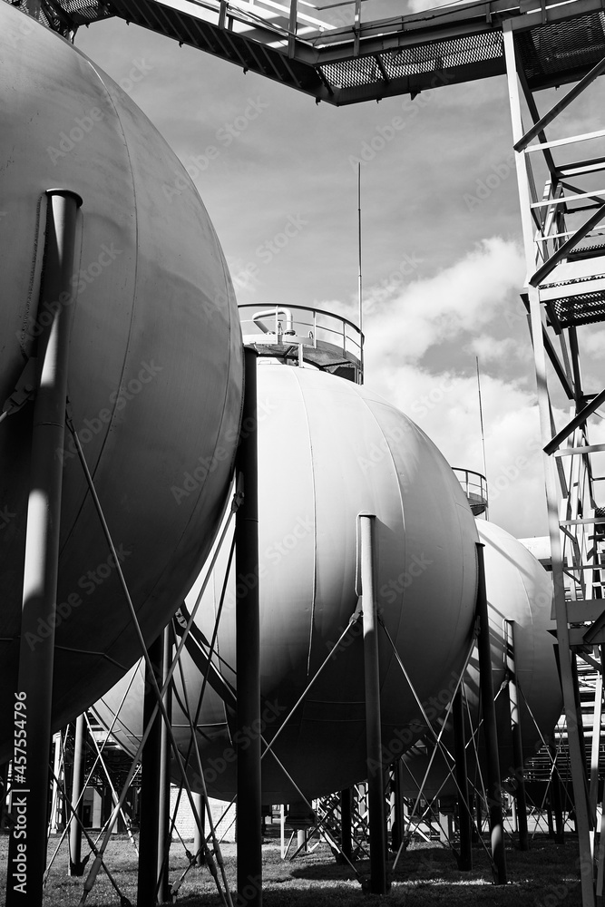 Industrial landscape bottom up view on several spherical gasholders tanks with lightning protection and safety valve on modern chemical production. Black and white industrial petrochemical background.
