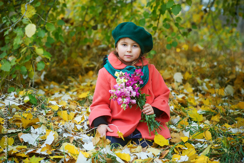 Portrait of a little girl in a coat with autumn flowers