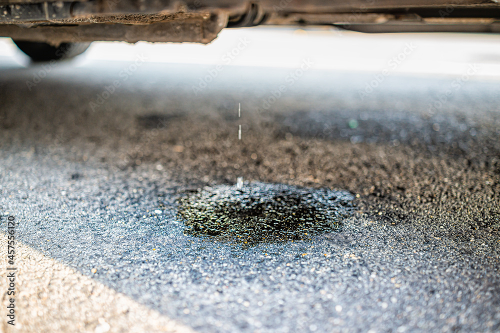 Parked car on street road with macro closeup of vehicle leaking fuel ...
