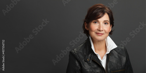 Middle aged well looking woman portrait against dark solid background.