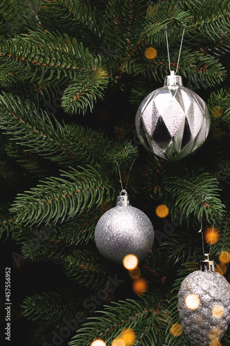 Metallic silver Christmas decorations hanging on a fir tree. New Year ornaments with olace for text. photo