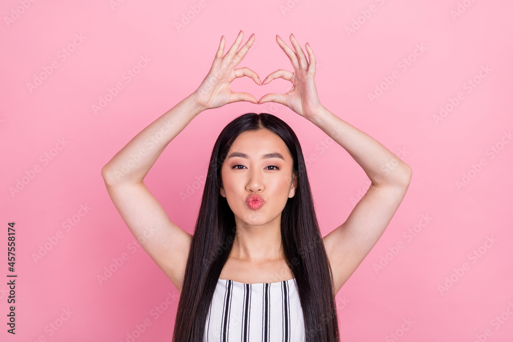 Photo of adorable pretty young lady wear striped outfit showing fingers heart sending you kiss isolated pink color background Photo of adorable pretty young lady wear striped outfit showing fingers heart sending you kiss isolated pink color background