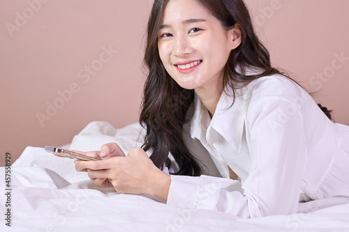woman smile and use phone on bed