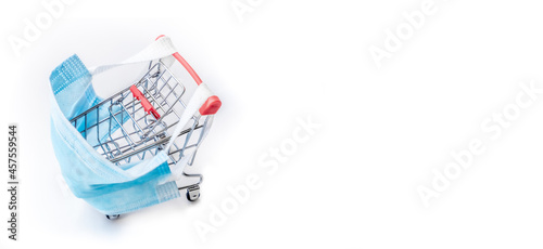 Shopping cart with blue protective medical mask against coronavirus. Safe and online shopping on quarantine concept. Light background, copy space, isolate. space for text