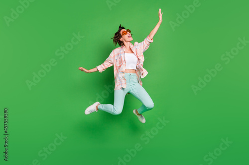 Full body photo of cheerful joyful happy woman jump up wear summer sunglass look empty space isolated on green color background