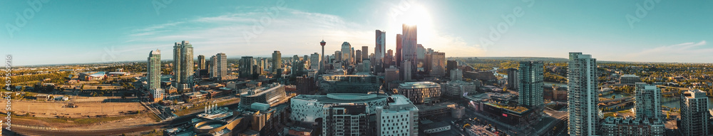 A panoramic image of downtown building and tower skyline against a shining sun and beautiful blue skies.