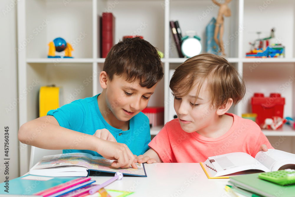 Happy student doing test in primary school. Children writing notes in classroom. School boys doing homework together. Happy student doing test in primary school. Children writing notes in classroom. School boys doing homework together.