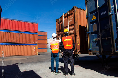 Marine and carrier insurance concept. Two harbor man working at container yard. Foreman control loading Containers box at shipping port. Business logistic Import and export concept.