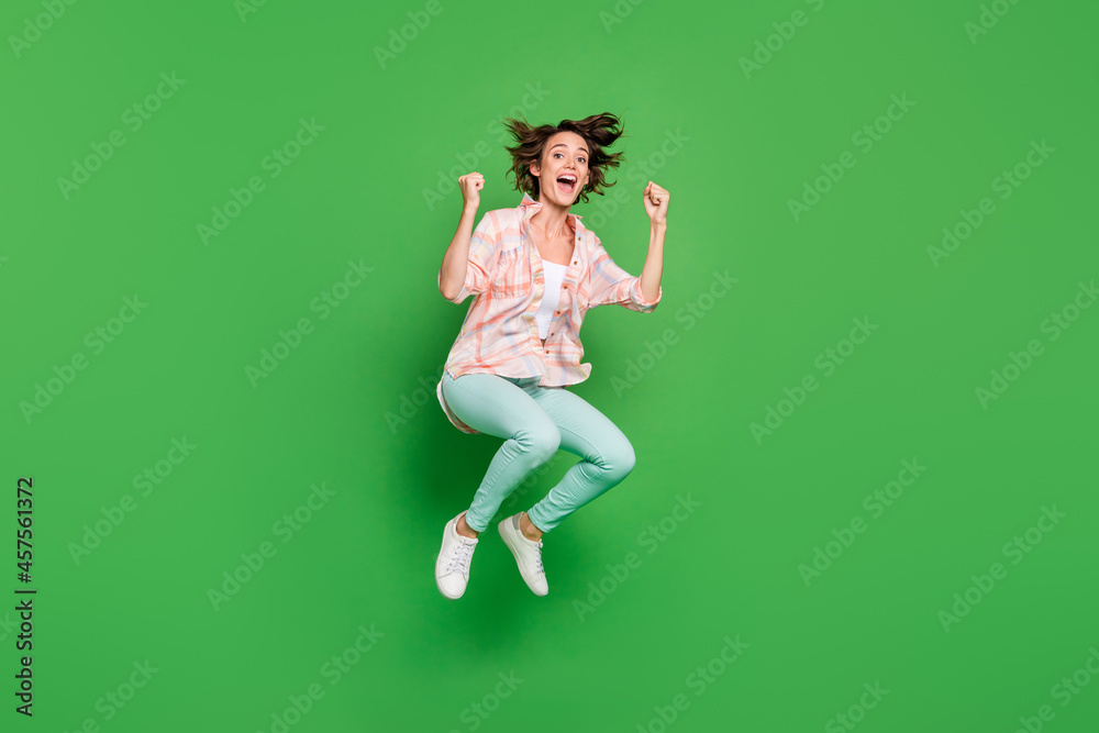 Full body photo of joyful amazed shocked young woman jump up winner sale isolated on green color background