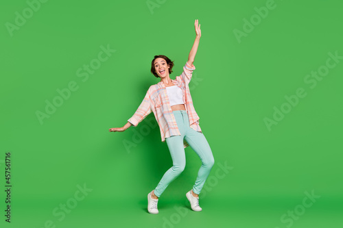 Full size photo of excited positive woman good mood raise hands weekend smile isolated on green color background