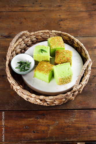 Bolu pandan tape keju or Pandan Tape Cheese Sponge cake (slice). cake with pandanus, cheese, and tape flavor. raisin and grated cheese as topping. photo