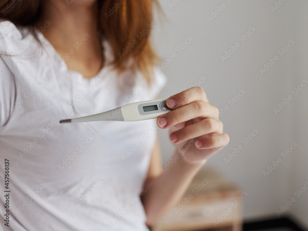 thermometer in the hands of a woman in a white t-shirt temperature check thermometer in the hands of a woman in a white t-shirt temperature check