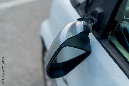 Broken off side rearview mirror on car. White automobile on road after accident.